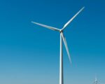 Modern wind turbine in a clear blue sky representing renewable energy technology